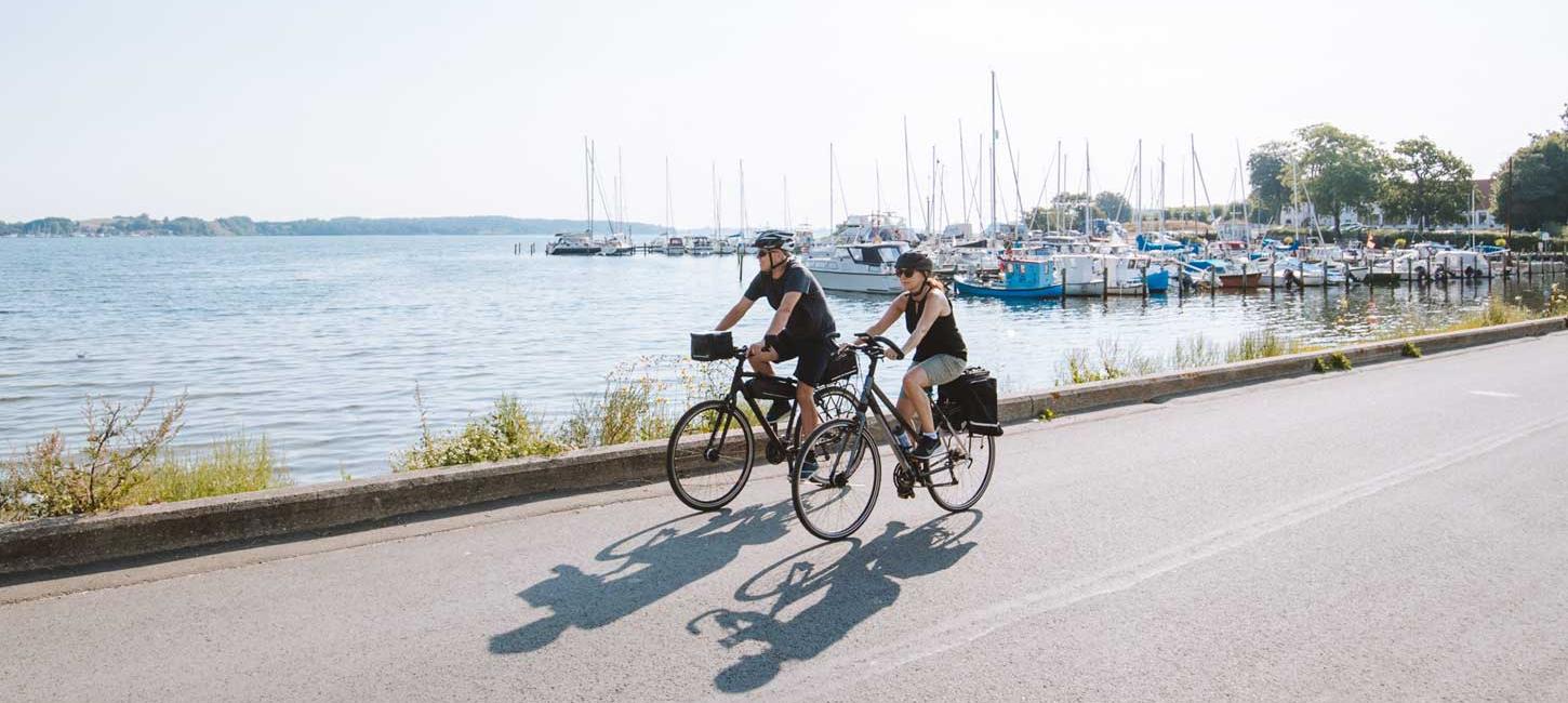 Pärchen fährt Fahrrad am Yachthafen von Kalvø