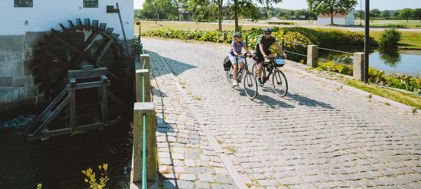 Pärchen fährt Fahrrad an der alten Schlossmühle in Aabenraa