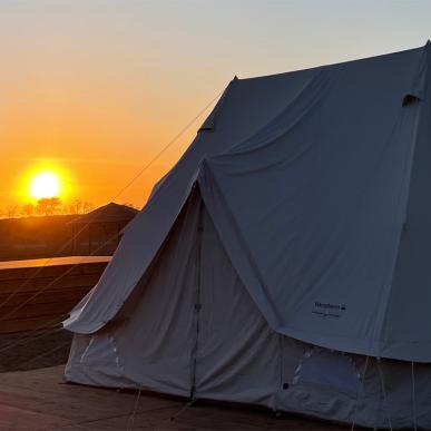 Glampingtelt på Marsk Camp med solnedgang i baggrunden