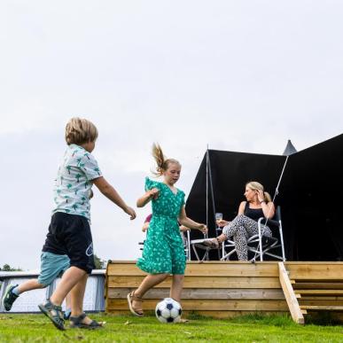 Børn spiller bold foran MOJN telt på Lærkelunden Camping