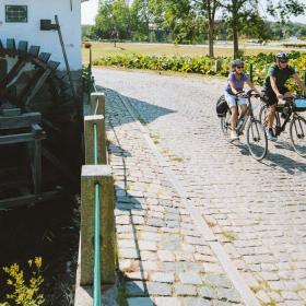 Pärchen fährt Fahrrad an der alten Schlossmühle in Aabenraa