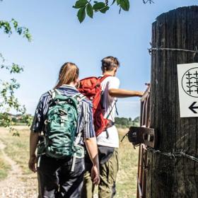 Vandrere på Camino Haderslev Næs med vejviserskilt i forgrunden
